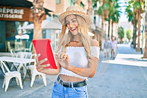 Young blonde tourist girl smiling happy using touchpad at the city