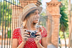 Young blonde tourist woman wearing summer style using vintage camera at the city