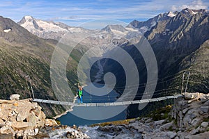 Young blonde trekker woman traversing a wooden bridge near Olperer Refuge in the Zillertal Alps, Austria photo