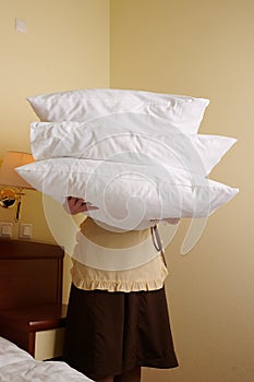 Young blonde woman 39 years old in the uniform of a hotel maid. Next to a large double bed. Change bed linen and bedding