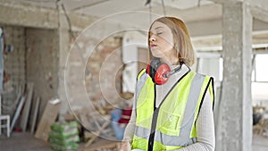 Young blonde woman architect taking out hardhat tired at construction site