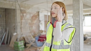 Young blonde woman architect using hardhat as a hand fan at construction site