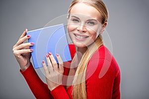 Young blonde woman with beautiful healthy long hair and natural make up holds a gift box
