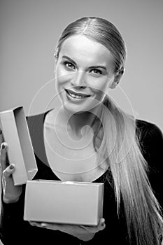 Young blonde woman with beautiful healthy long hair and natural make up holds a gift box