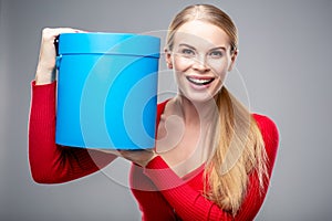 Young blonde woman with beautiful healthy long hair and natural make up holds a gift box