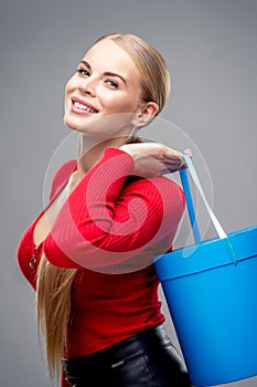 Young blonde woman with beautiful healthy long hair and natural make up holds a gift box