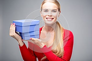 Young blonde woman with beautiful healthy long hair and natural make up holds a gift box