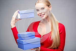 Young blonde woman with beautiful healthy long hair and natural make up holds a gift box