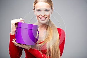 Young blonde woman with beautiful healthy long hair and natural make up holds a gift box. Fashion beauty portrait