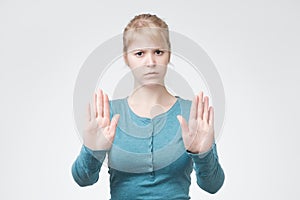 Young blonde woman in blue clothes making a rejection pose