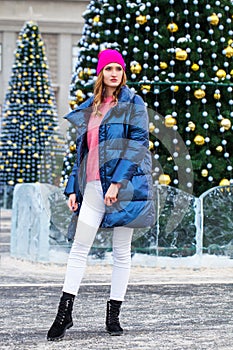 Young blonde woman in blue down jacket in winter street