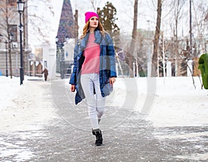 Young blonde woman in blue down jacket in winter street