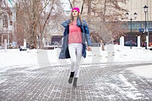 Young blonde woman in blue down jacket in winter street