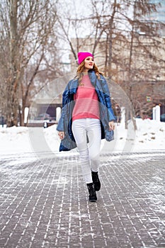 Young blonde woman in blue down jacket in winter street