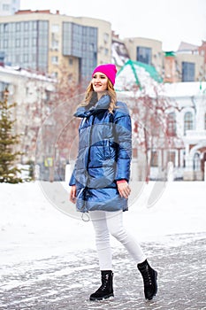 Young blonde woman in blue down jacket in winter street