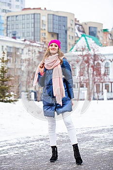 Young blonde woman in blue down jacket in winter street