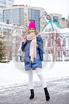 Young blonde woman in blue down jacket in winter street