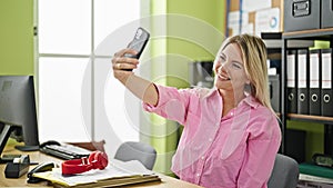 Young blonde woman business worker make selfie by smartphone at office