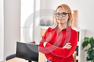 Young blonde woman business worker smiling confident standing with arms crossed gesture at office