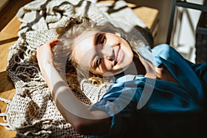 Young blonde woman chilling near panoramic window in her living room, sunny weather