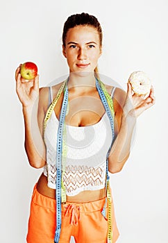 Young blonde woman choosing between donut and apple fruit isolated on white background, lifestyle people concept