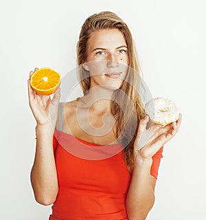 Young blonde woman choosing between donut and orange fruit on white background, lifestyle people concept