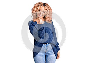 Young blonde woman with curly hair wearing casual winter sweater beckoning come here gesture with hand inviting welcoming happy