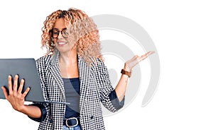 Young blonde woman with curly hair working using laptop celebrating victory with happy smile and winner expression with raised