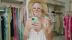 Young blonde woman customer make selfie by smartphone at clothing store