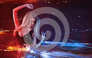 Young blonde woman dancing at night disco club. Motion blur