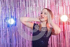 Young blonde woman dancing at night disco club. Party, holidays and celebration concept.