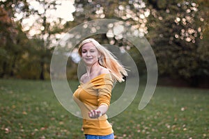 Young blonde woman dancing, turning around in the park