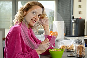 Young blonde woman eating cereals in the morning