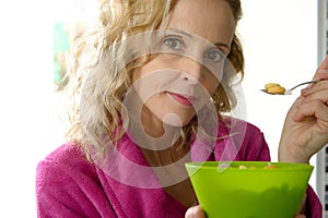 Young blonde woman eating cereals in the morning