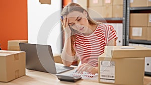 Young blonde woman ecommerce business worker doing account stressed at office