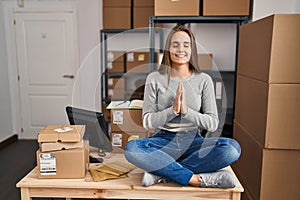 Young blonde woman ecommerce business worker doing yoga sitting on table at office