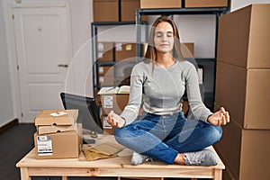 Young blonde woman ecommerce business worker doing yoga sitting on table at office