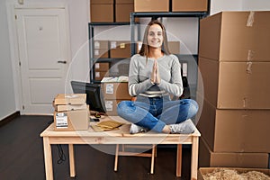 Young blonde woman ecommerce business worker doing yoga sitting on table at office