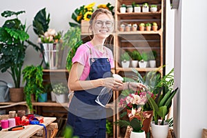 Young blonde woman florist using diffuser working smiling at flower shop