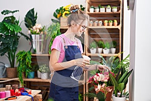 Young blonde woman florist using diffuser working smiling at flower shop