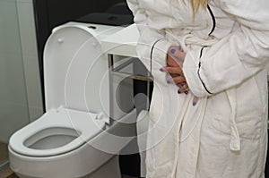 Young blonde woman getting sick, with nausea in the bathroom