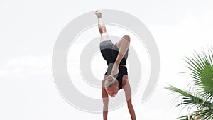 A young blonde woman gymnast doing handstand on the high bars