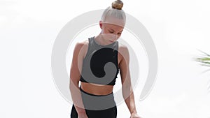 A young blonde woman gymnast doing stretching exercises on the open sports ground using high bars