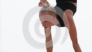 A young blonde woman gymnast uses high bars to the handstand