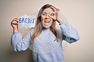 Young blonde woman holding brexit banner from political referendum over isolated background with happy face smiling doing ok sign