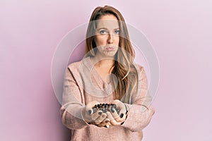 Young blonde woman holding coffee beans with hands depressed and worry for distress, crying angry and afraid