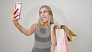 Young blonde woman holding shopping bags make selfie by smartphone over isolated white background