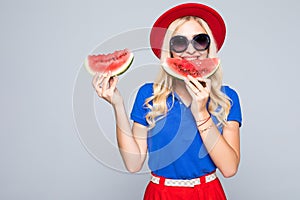 Young blonde woman holding two slice of watermelon in hands and smiling happy wearing in color clothes, summertime concept and moo