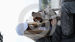 Young blonde woman hugs a dog in a spring park. Female owner with a Jack Russell terrier puppy on a walk, a close-up