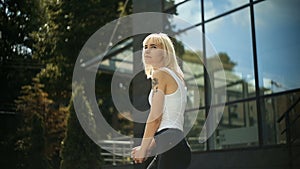 Young blonde woman kneads wakes up enjoys the rays of the sun against the background of a glass wall